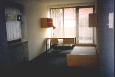 Blick auf Bett, Schreibtisch und Fensterfront